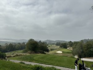 Golf course with rolling hills and lush greenery, illustrating concepts of golf handicap and slope, featuring fairways, sand traps, and a golfer preparing for a shot.