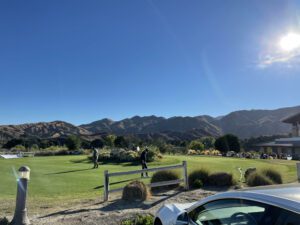 Golfers enjoying a sunny day on the lush green course at Sand Canyon Golf, with picturesque mountains and clear blue skies in the background at Sand Canyon Country Club.